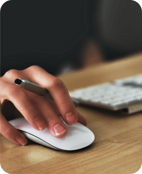 Hand holding a white mouse with a pen between the fingers