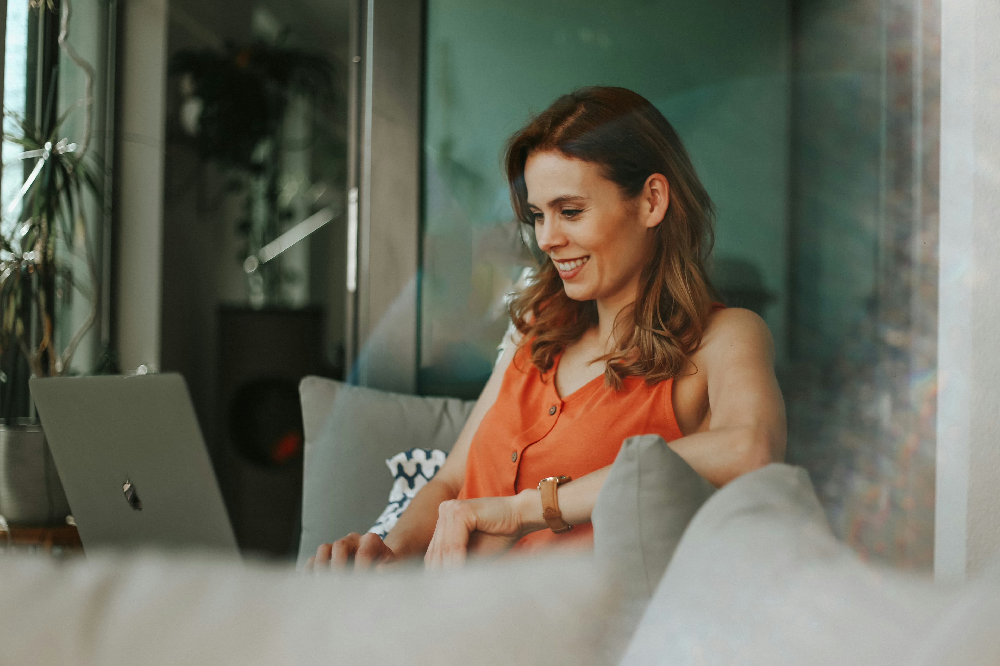 Smiling woman sitting on a sofa working on a laptop